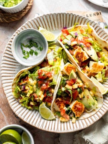 Halloumi Tacos with crispy halloumi, fresh mango salsa, creamy avocado, and crunchy cabbage served with lime wedges.