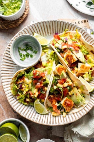 Halloumi Tacos with crispy halloumi, fresh mango salsa, creamy avocado, and crunchy cabbage served with lime wedges.