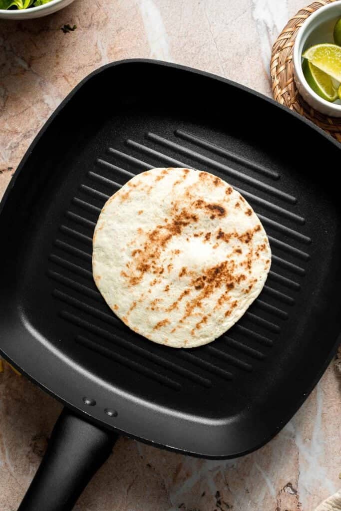 Warming a tortilla in a grill pan.
