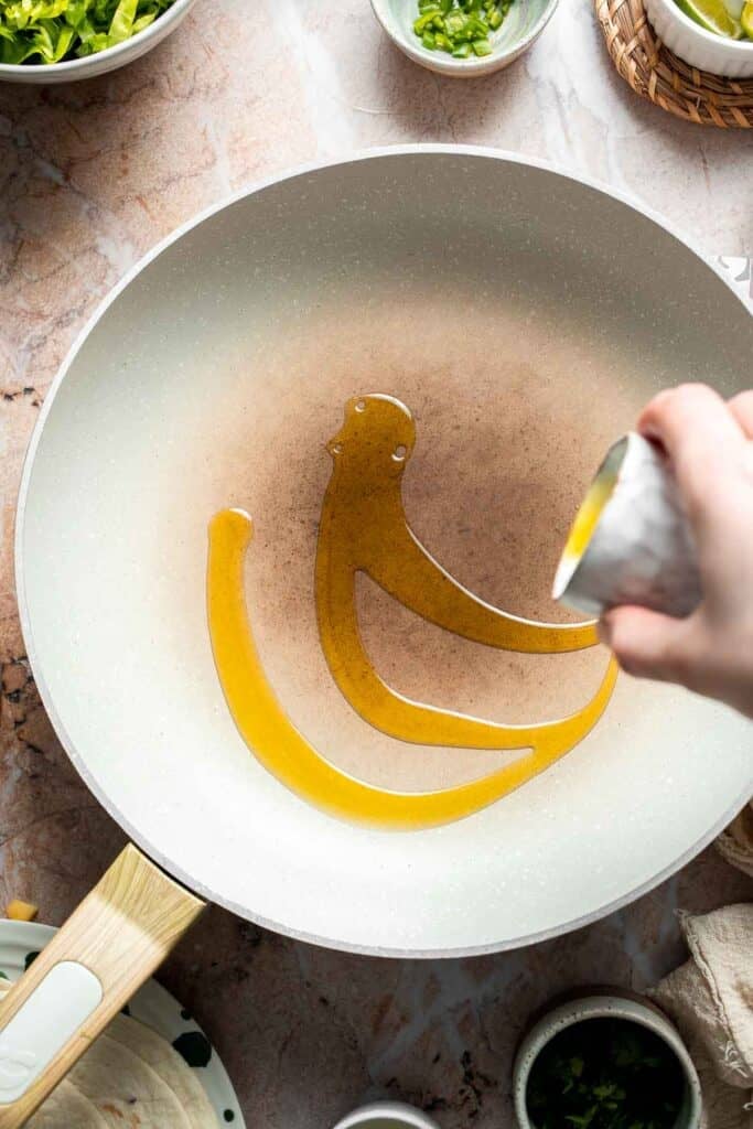 Adding olive oil to a non-stick skillet.