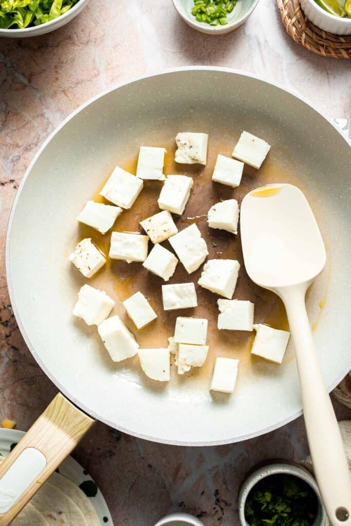 Halloumi cubes cooking in a skillet.