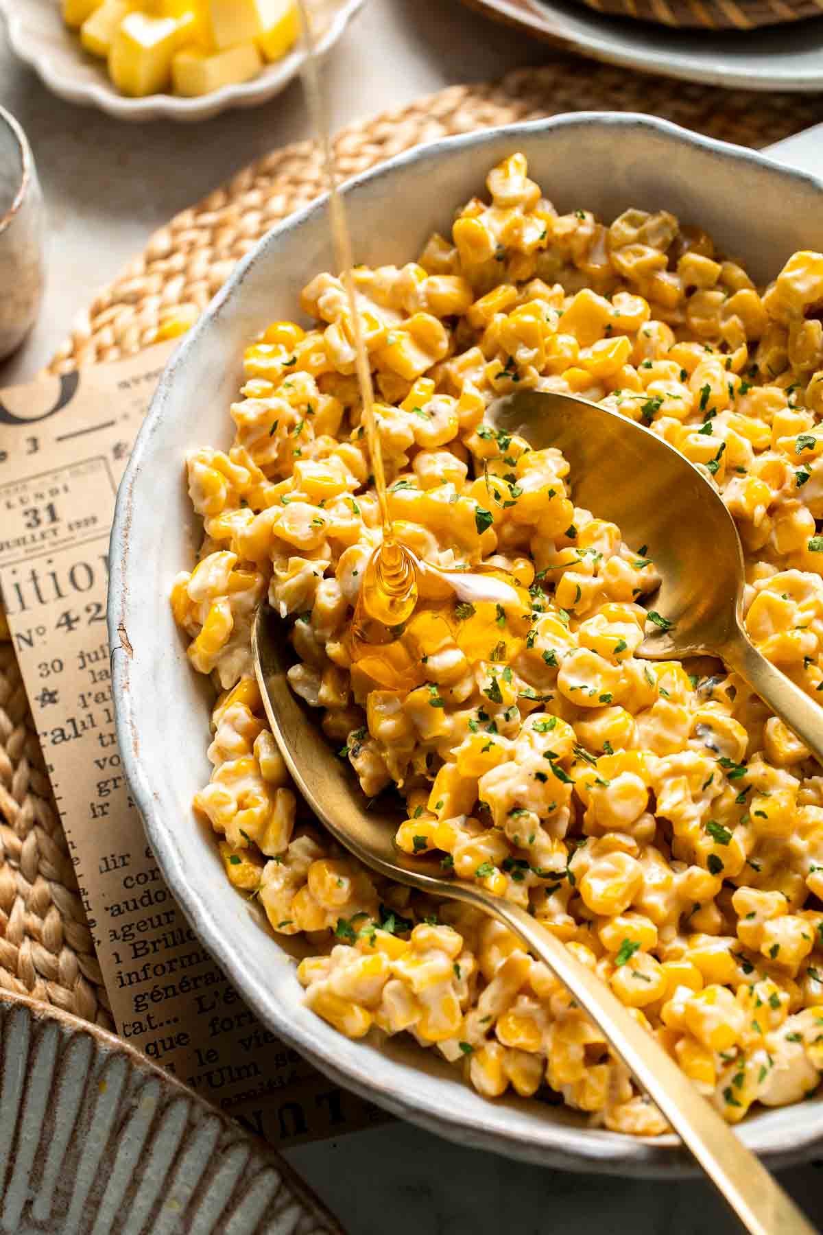 Honey butter skillet corn being served into a bowl with a drizzle of honey