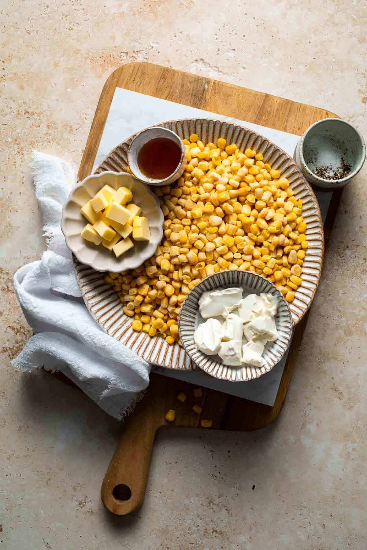 Ingredients for honey butter skillet corn including butter, honey, cream cheese, and frozen corn arranged on a wooden board
