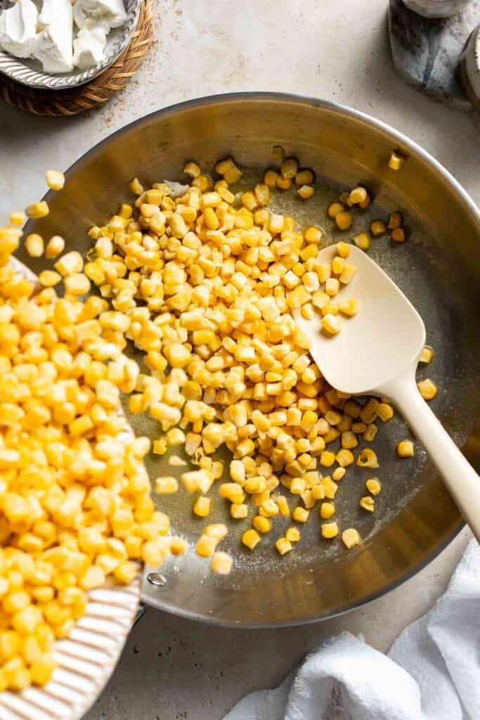 Frozen corn added to melted butter in a skillet