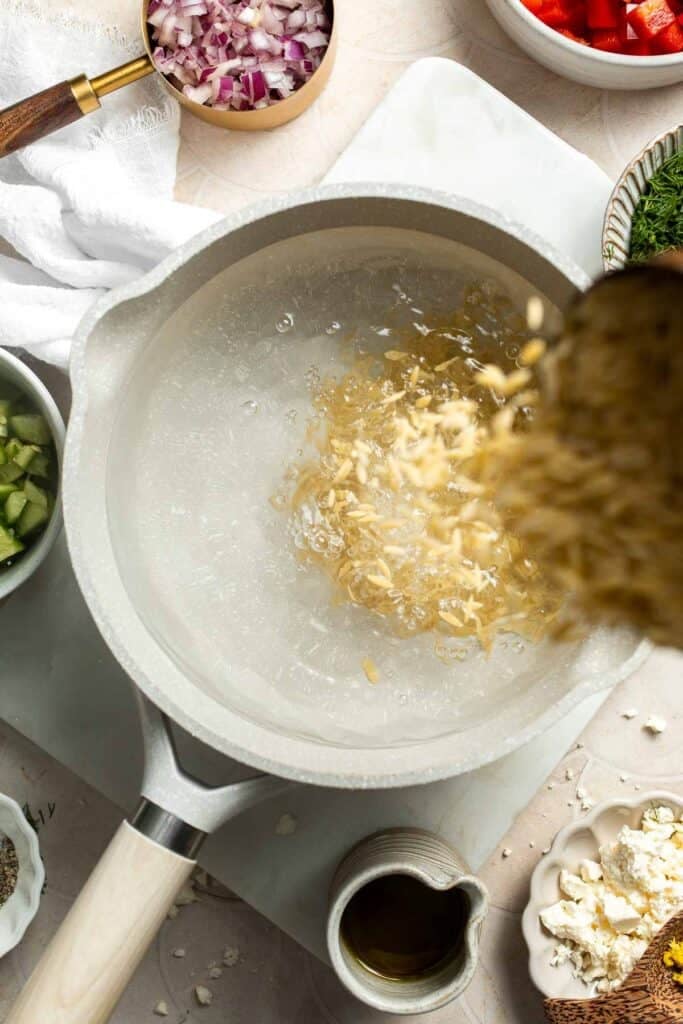 Adding dry orzo pasta to a pot of boiling water