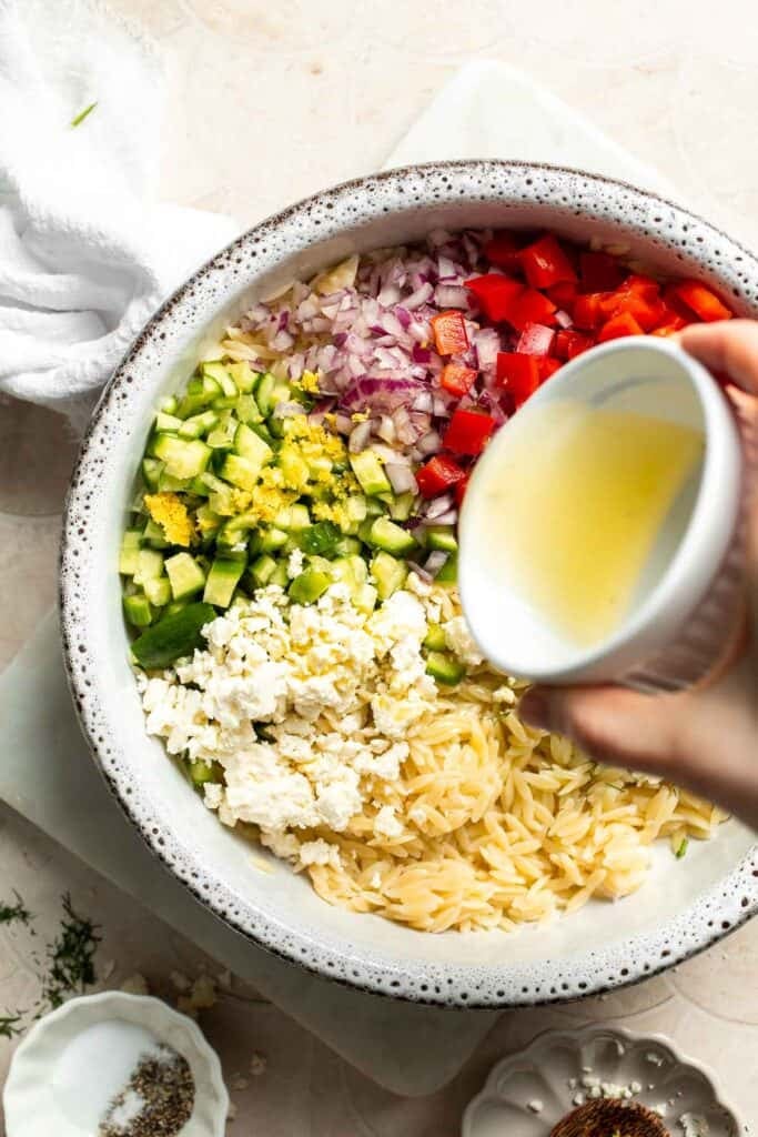 Adding fresh lemon juice to Lemon Orzo Salad.