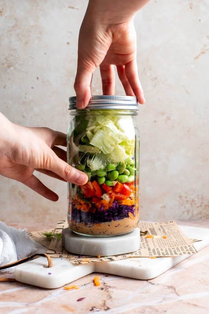 Closing the lid of the assembled Asian peanut mason jar salad