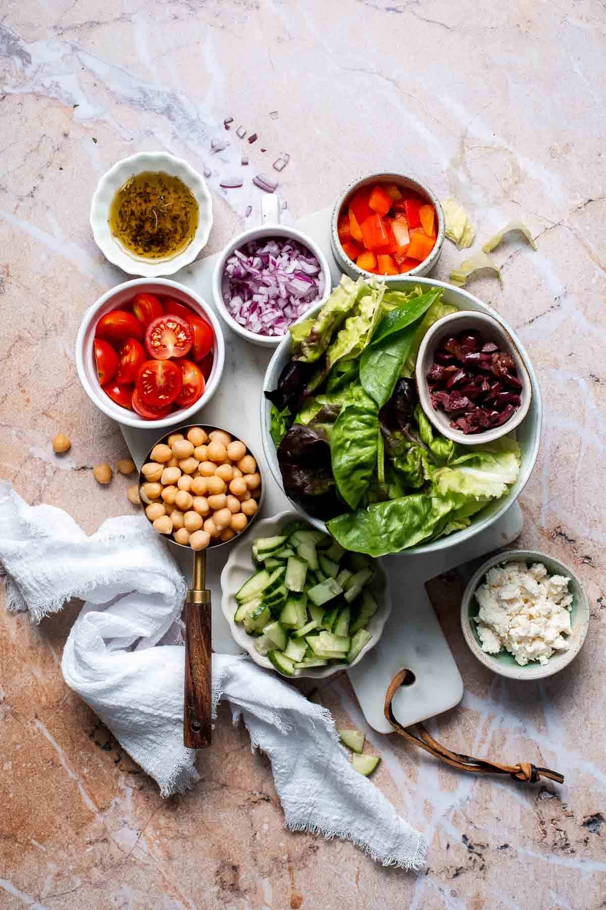 Overhead view of Mediterranean mason jar salad ingredients including chickpeas, feta, and tomatoes in bowls