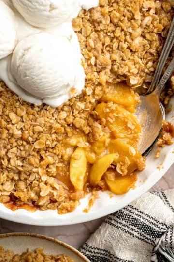 Warm Peach Crisp with juicy baked peaches, a buttery oat topping, and vanilla ice cream.