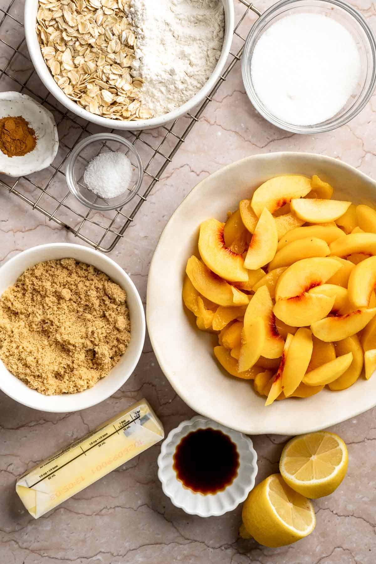 Ingredients for Peach Crisp including fresh peaches, oats, flour, brown sugar, butter, cinnamon, lemon, and vanilla.