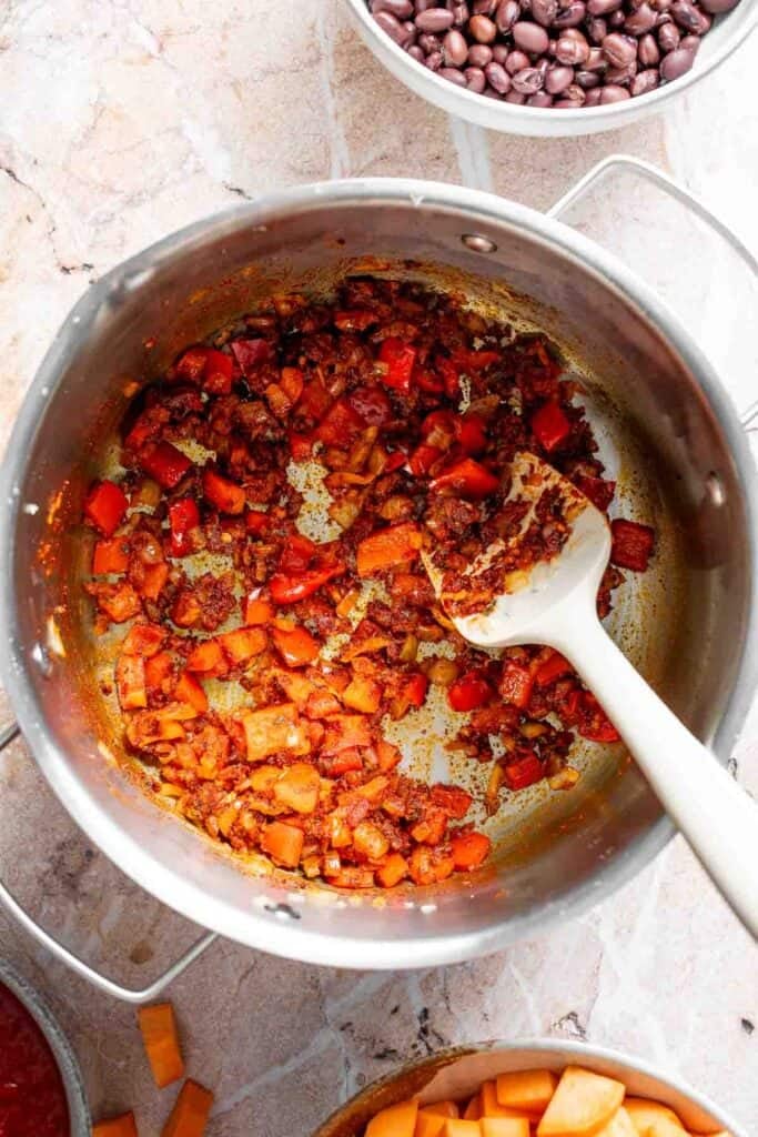 Toasted spices stirred into sautéed vegetables in a Dutch oven