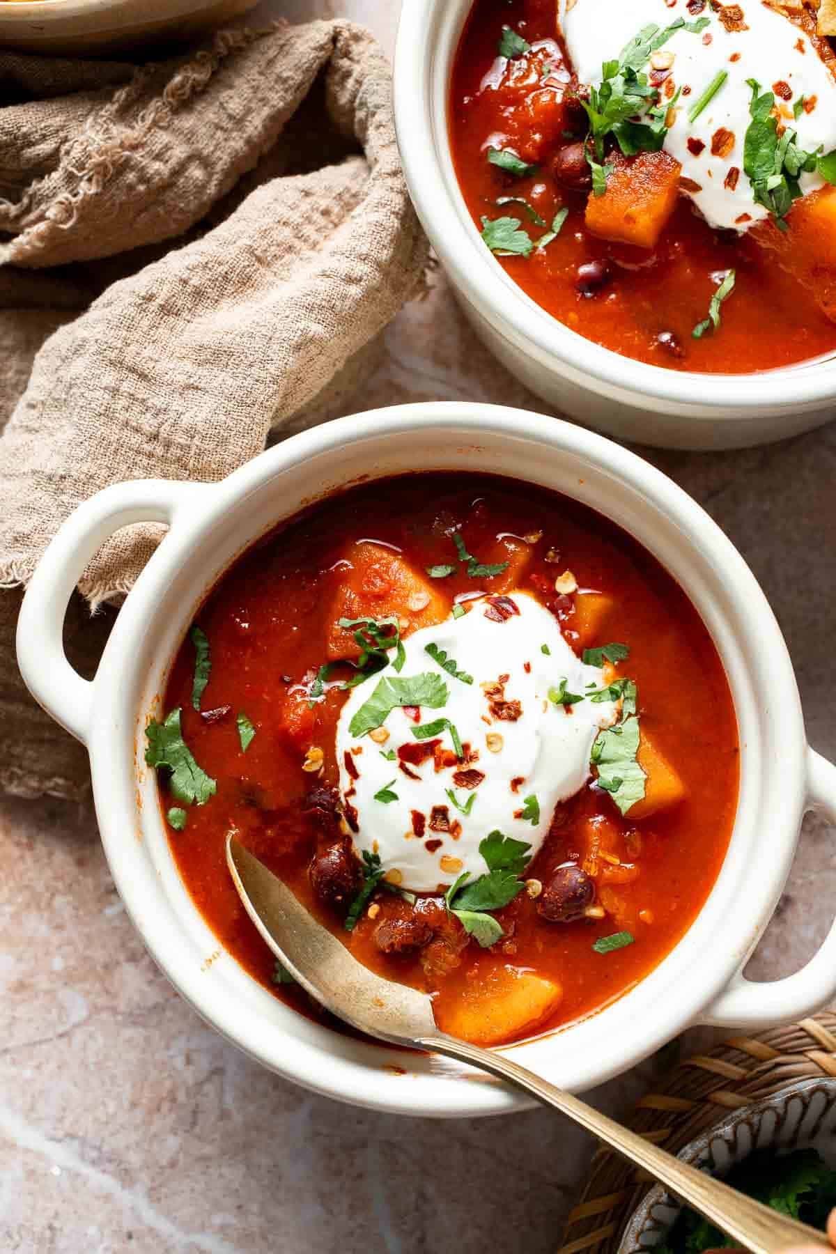 Bowls of sweet potato black bean chili topped with sour cream and cilantro