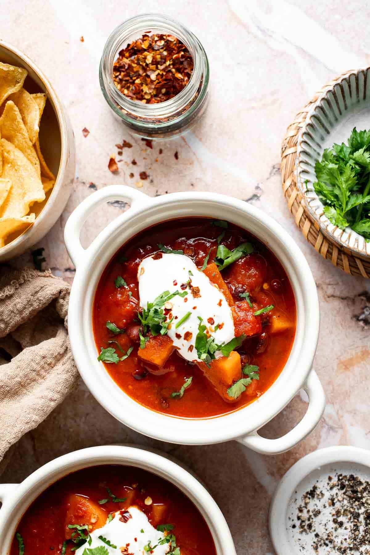 Overhead view of sweet potato black bean chili in bowls with tortilla chips and toppings