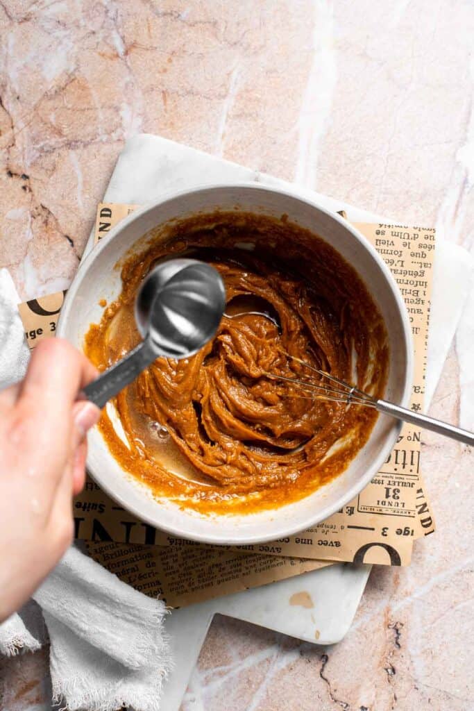 Warm water being added to Thai peanut dressing to thin the consistency