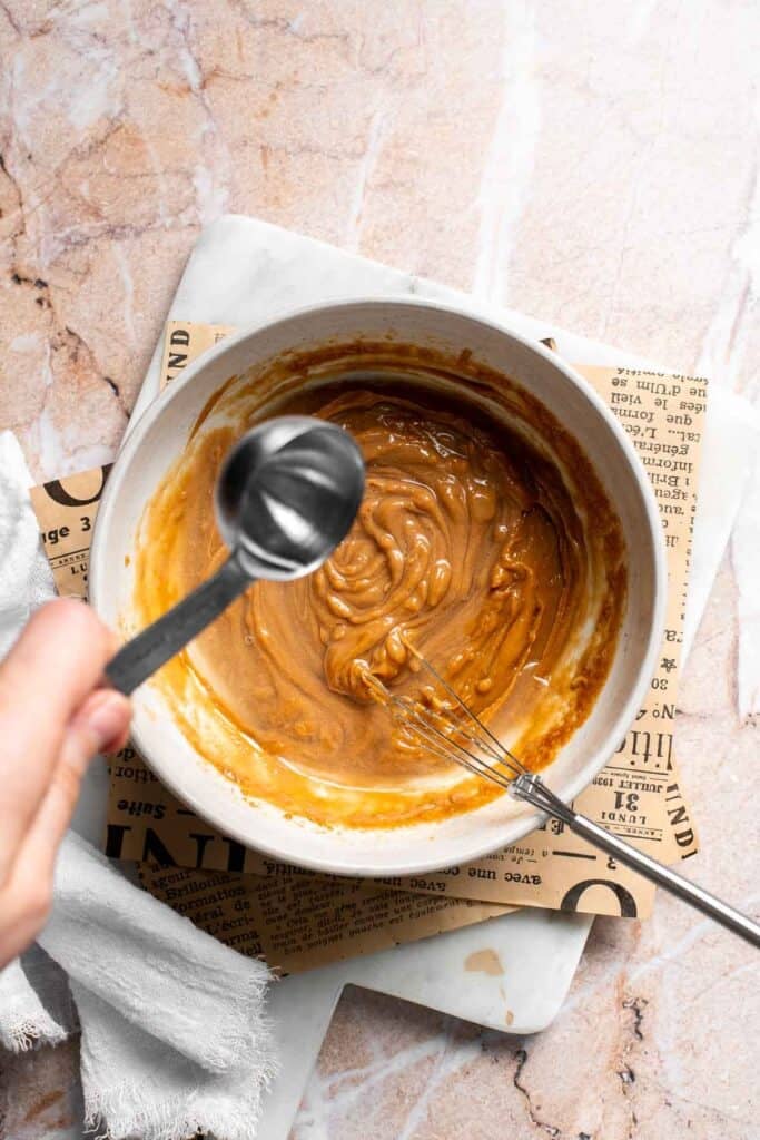 Warm water being added to Thai peanut dressing to thin the consistency