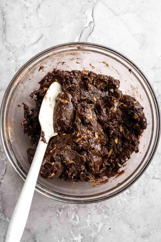 Chocolate chips being folded into fudgy zucchini brownie batter