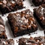 Stack of fudgy zucchini brownie squares topped with melted chocolate chips and a sprinkle of flaky salt