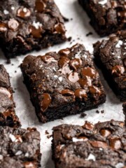Stack of fudgy zucchini brownie squares topped with melted chocolate chips and a sprinkle of flaky salt