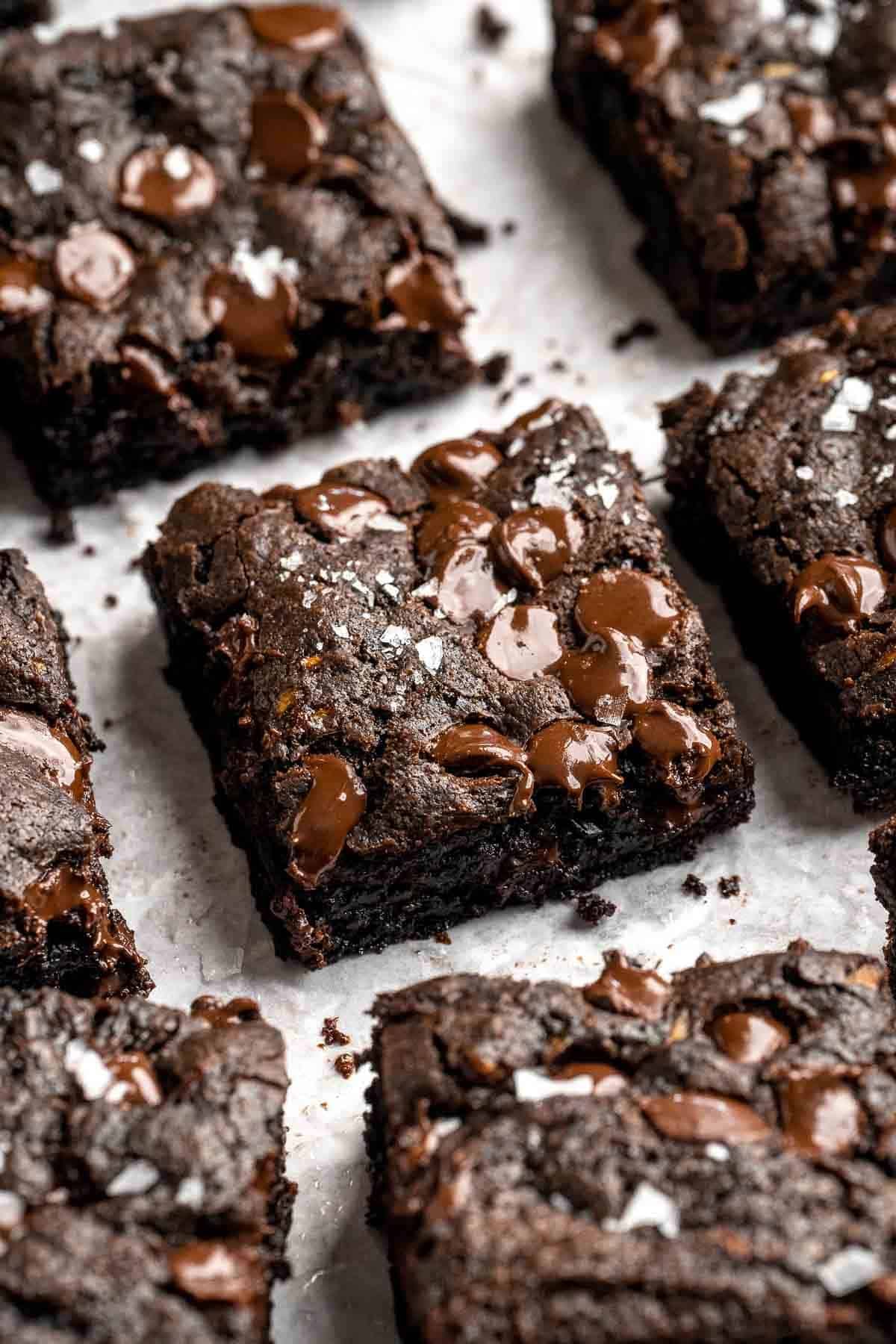 Stack of fudgy zucchini brownie squares topped with melted chocolate chips and a sprinkle of flaky salt