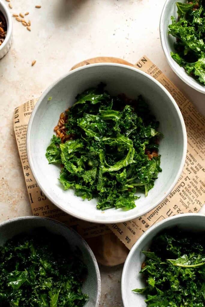 Kale added to a bowl with farro