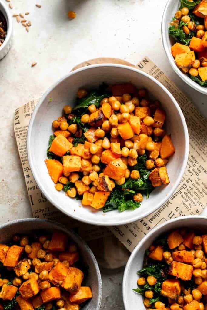 Roasted sweet potatoes and chickpeas added to a bowl with farro and kale