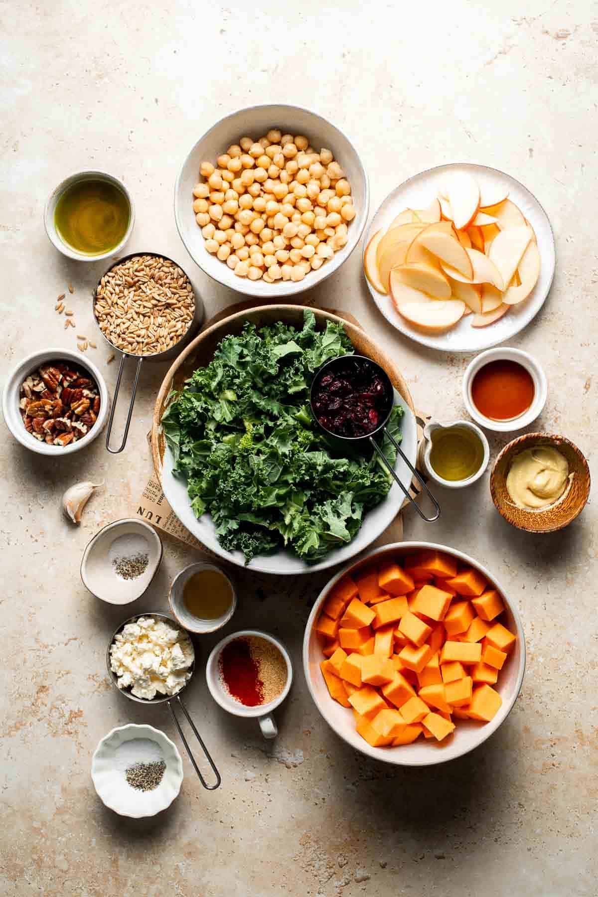 Ingredients for harvest grain bowl including farro, kale, sweet potato, and chickpeas arranged in bowls