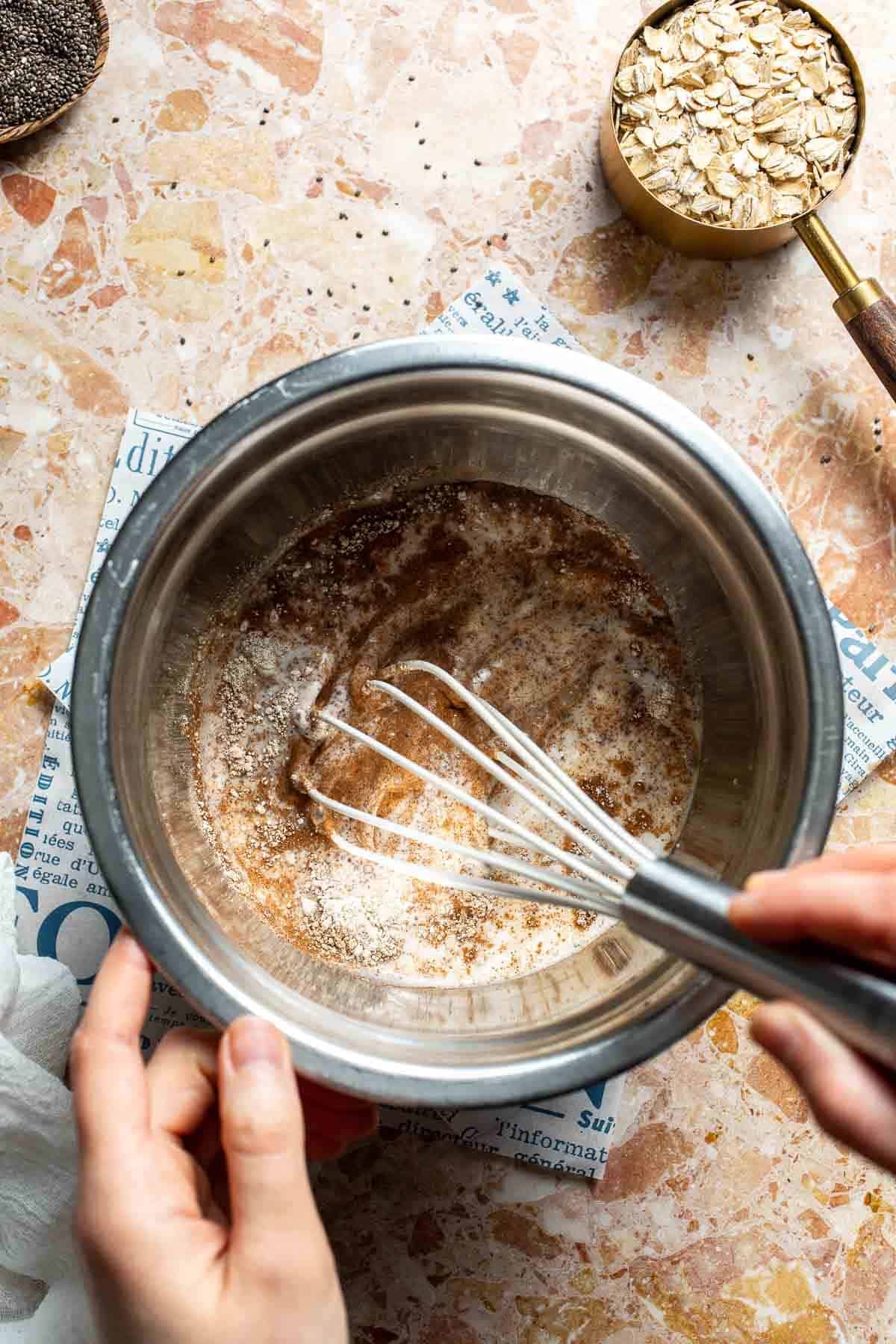 Wet ingredients and protein powder being whisked together in a bowl