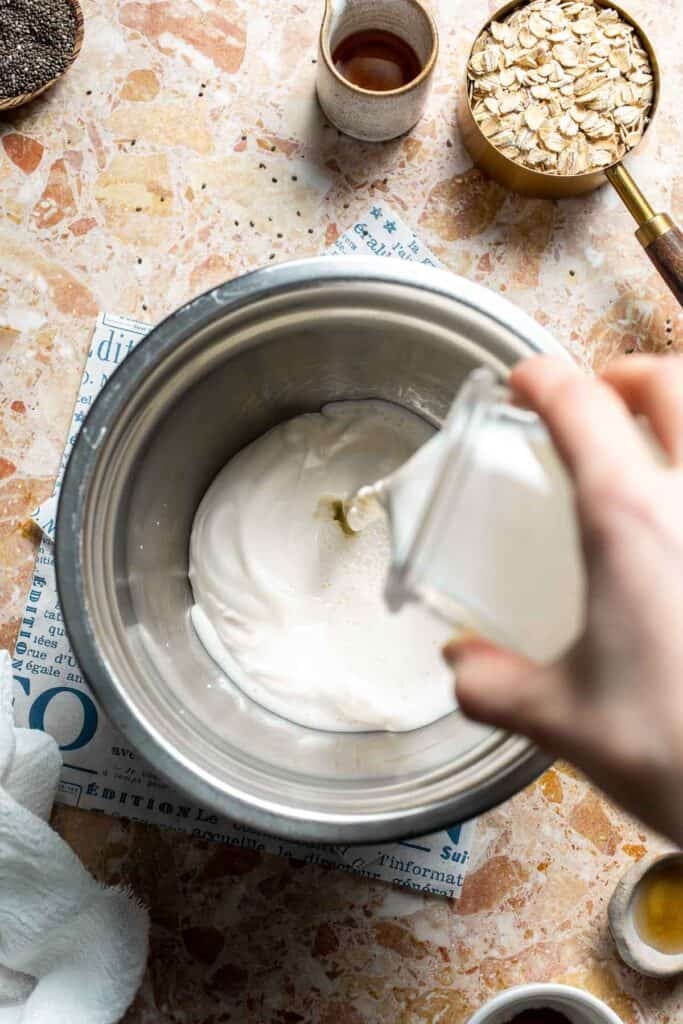 Milk being poured into a bowl of yogurt