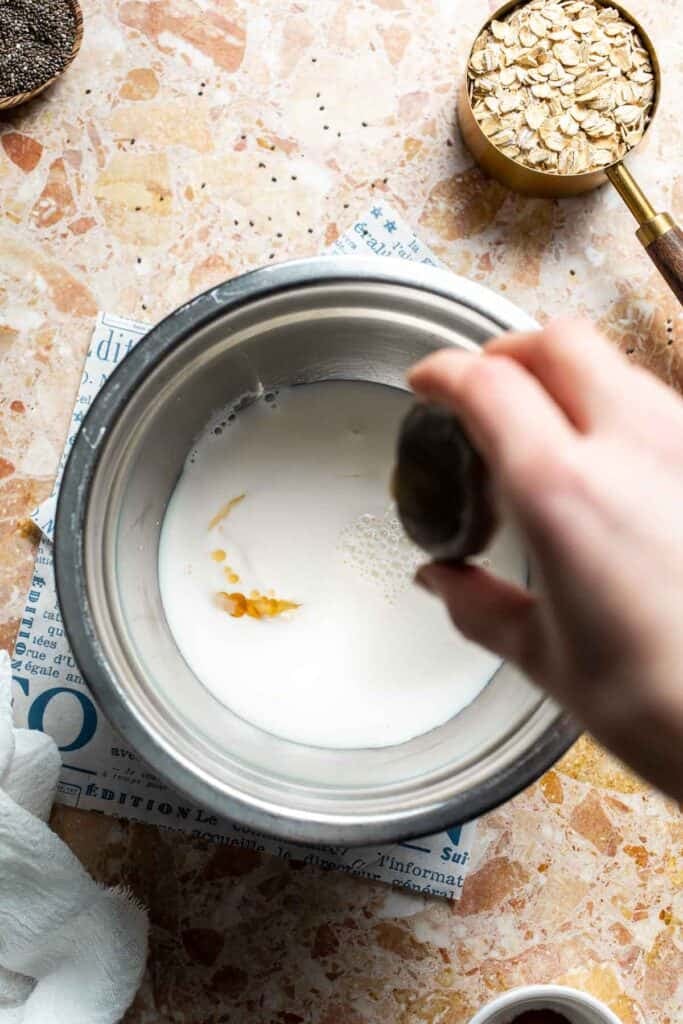 Vanilla extract being added into a bowl of yogurt and milk