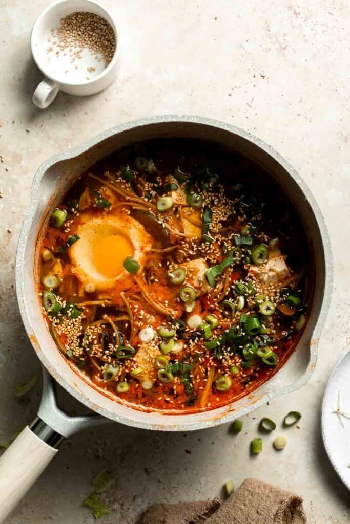 Overhead view of finished Korean tofu soup with egg and green onion in a pot