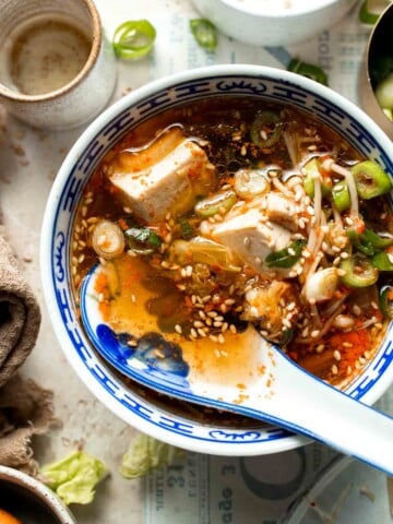 Korean tofu soup served in a blue and white bowl with sesame seeds and green onion