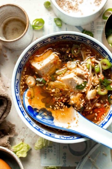 Korean tofu soup served in a blue and white bowl with sesame seeds and green onion