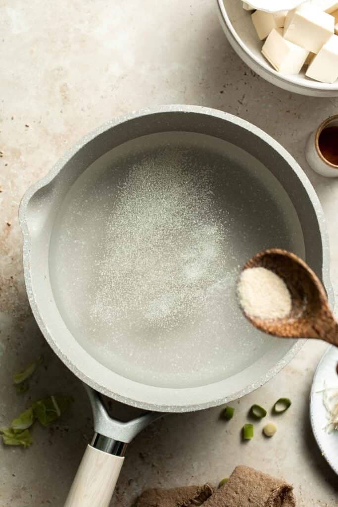 Dashi powder being added to water in a pot