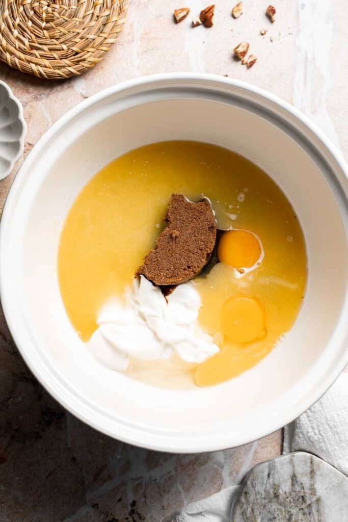 Brown sugar, eggs, sour cream, milk, and vanilla in a bowl before mixing