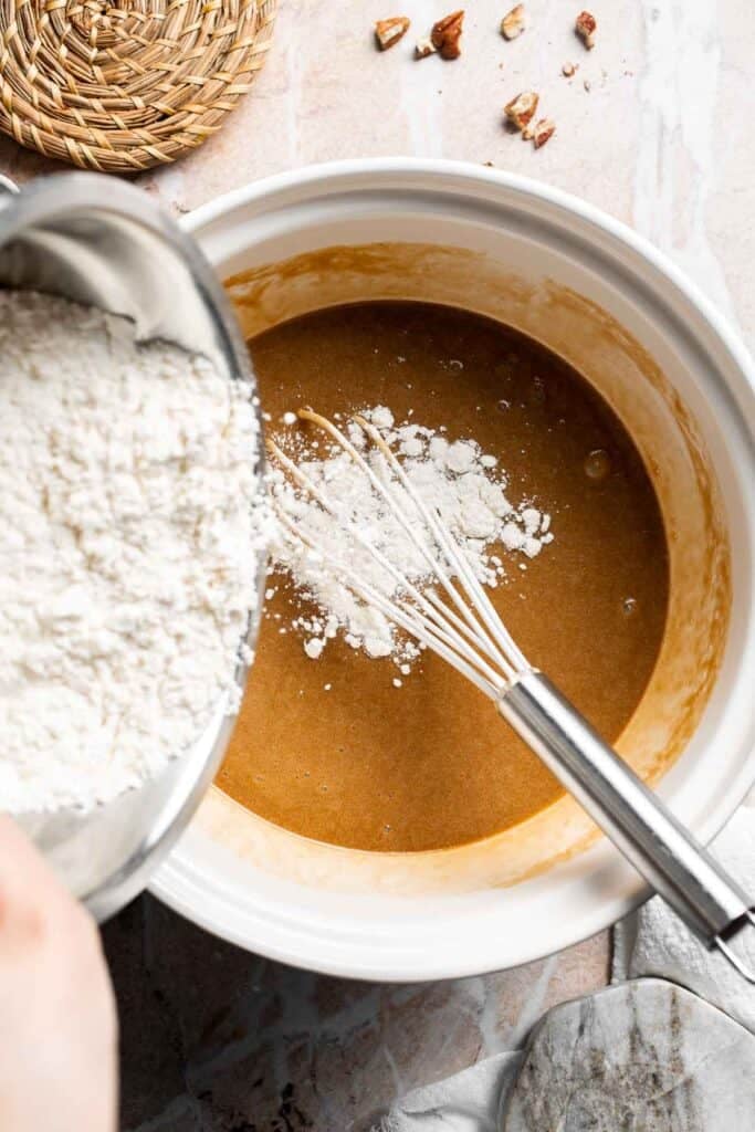 Dry ingredients being added to a bowl of whisked wet ingredients