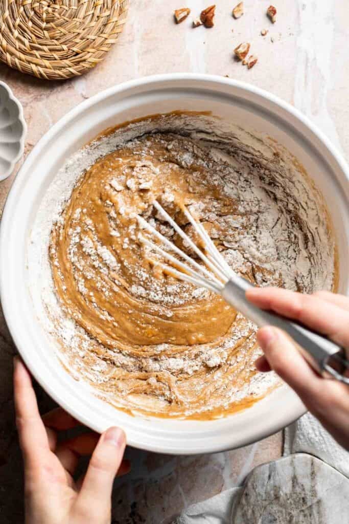 Batter being whisked together in a bowl with flour streaks visible