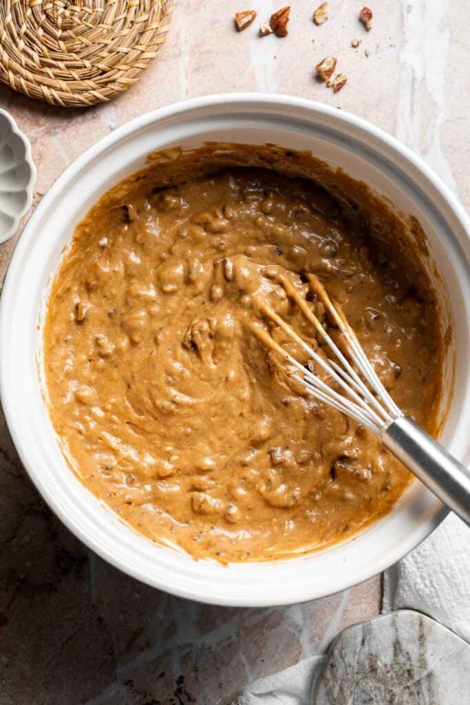 Pecans folded evenly into muffin batter in a bowl