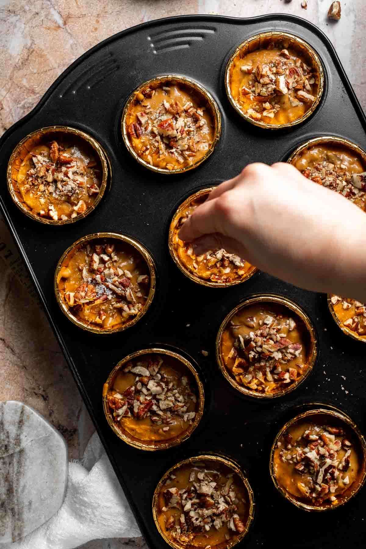 Coarse sugar being sprinkled over unbaked muffin batter