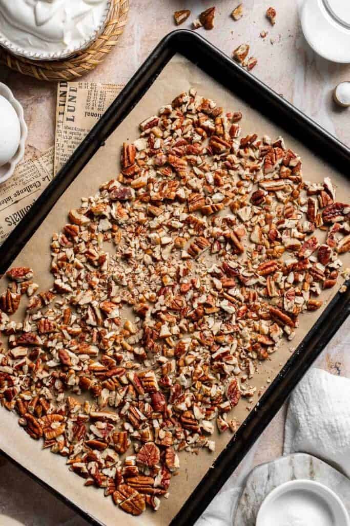 Chopped pecans spread on a baking sheet before toasting
