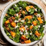 Roasted Sweet Potato Salad with Spinach served in a large bowl with caramelized sweet potatoes, feta, pecans, and cranberries in a maple Dijon dressing