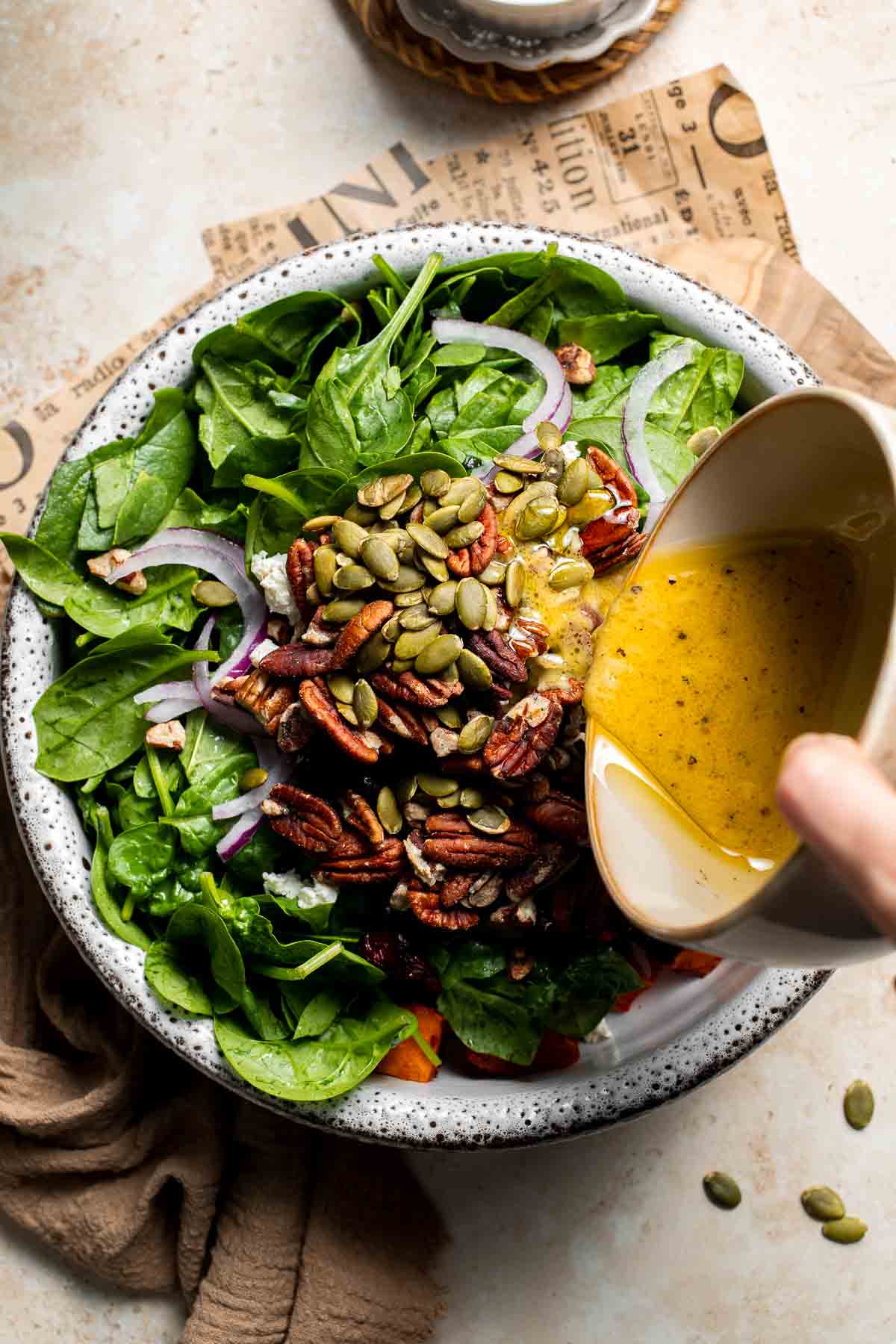Dressing being poured over a bowl of roasted sweet potato salad