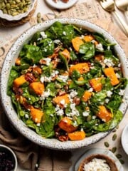 Roasted Sweet Potato Salad with Spinach served in a large bowl with caramelized sweet potatoes, feta, pecans, and cranberries in a maple Dijon dressing