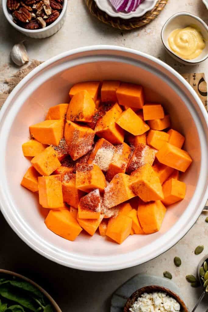 Diced sweet potatoes coated in oil and spices in a bowl