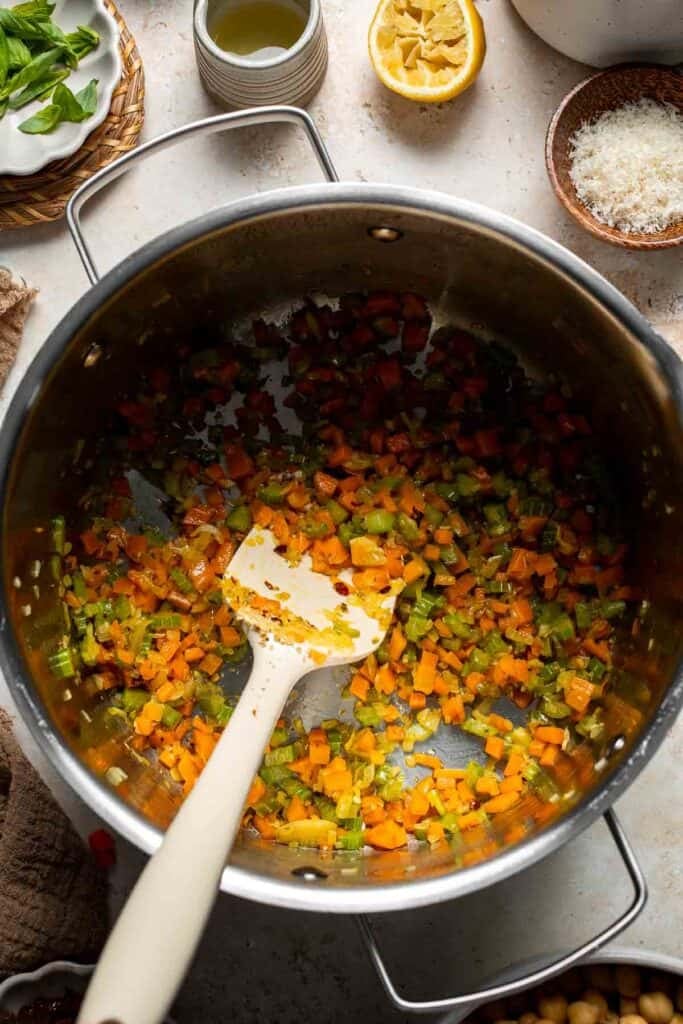 Sautéed vegetables being stirred in a pot with garlic and spices