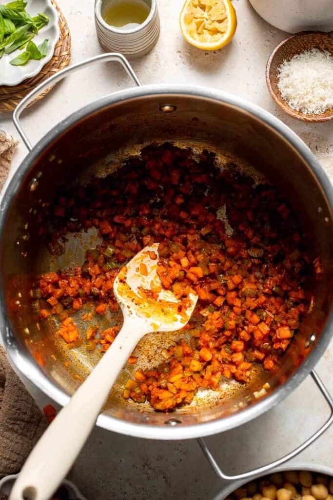 Tomato paste cooking with vegetables in a pot, stirred with a spoon