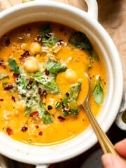 Close-up of a bowl of Tuscan chickpea soup garnished with Parmesan and herbs