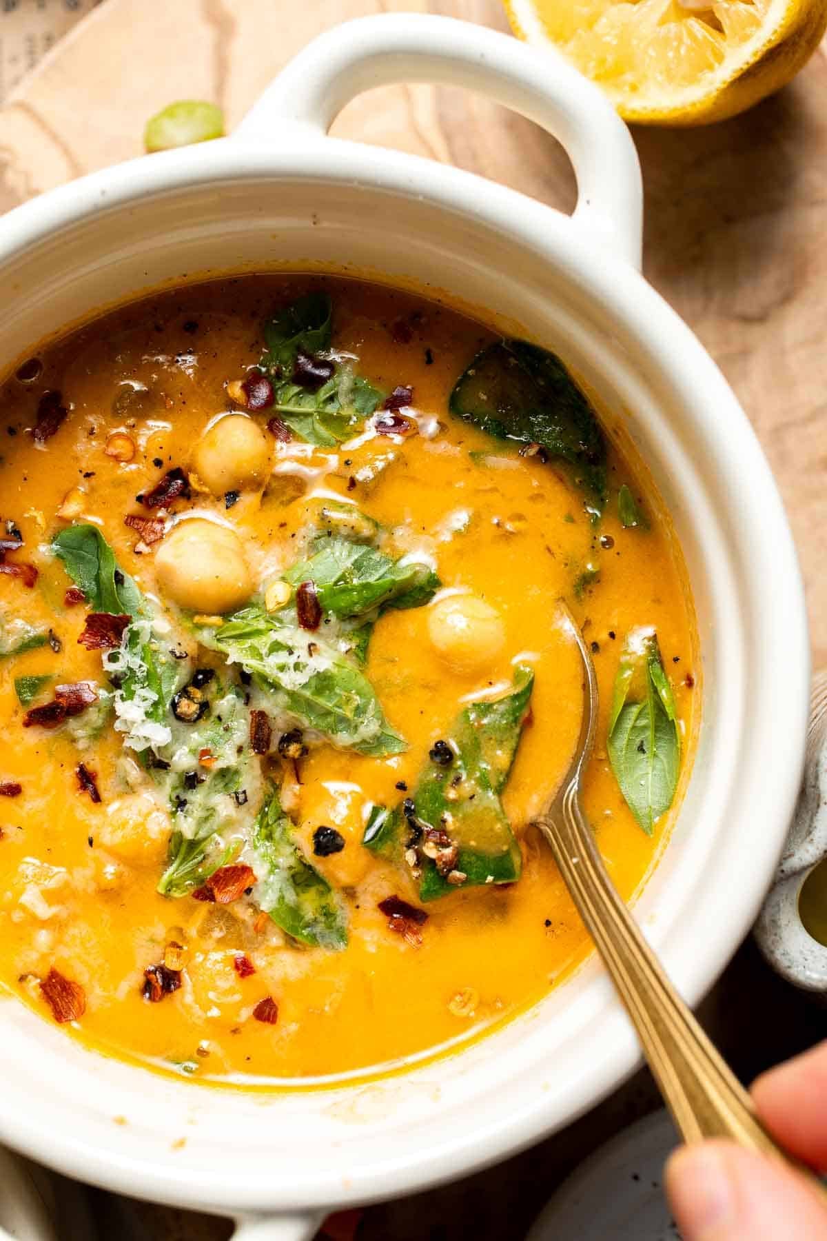 Close-up of a bowl of Tuscan chickpea soup garnished with Parmesan and herbs