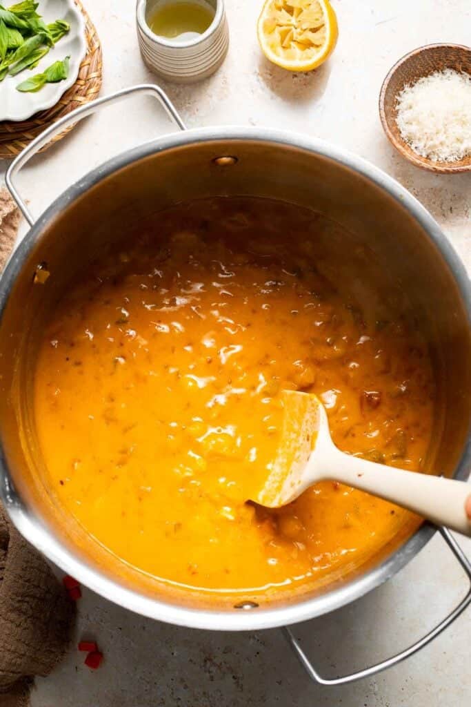 Blended soup being stirred back into the pot with a spoon