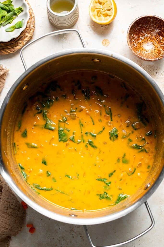 Spinach wilting into the creamy soup in a pot