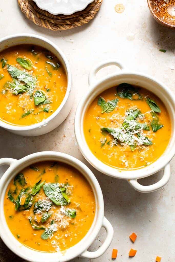 Three bowls of Tuscan chickpea soup garnished with fresh herbs